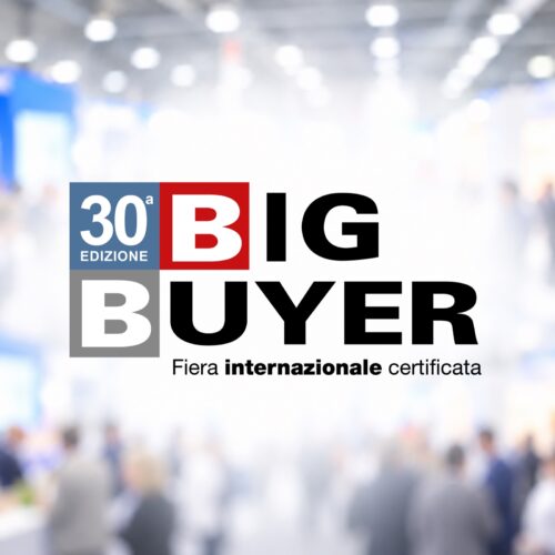 Logo Big Buyer 30ª edizione su sfondo sfocato di fiera internazionale con persone in movimento.